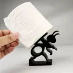 Close-up of the textured plastic ant figure holding a toilet paper roll, with soft natural lighting.