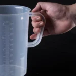 Transparent plastic lab beaker with measurement scale on kitchen counter