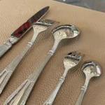 Elegant stainless steel flatware set with mirror finish arranged on a wooden table