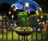 Solar frog garden light with umbrella illuminating a flower bed at dusk