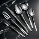 Elegant French stainless steel cutlery set with pointed tail handles on a wooden table