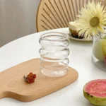 Set of glass cups with straws on a wooden table, filled with iced tea and lemon