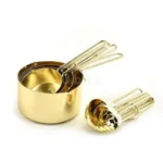 Set of stainless steel measuring cups with copper and rose gold finishes on wooden stand