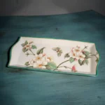 Floral ceramic toothbrush holder on vanity, with makeup brush holder and lotion bottle.