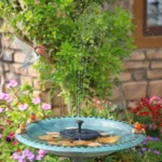 Outdoor bird bath fountain with solar panel and water spray in a garden