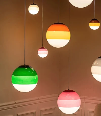 Green glass pendant lamp hanging over a wooden dining table in a cozy restaurant setting.