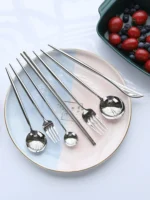 Elegant stainless steel flatware set with forks, spoons, and knives arranged on a wooden table
