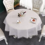 Round linen tablecloth with tassels on a dining table