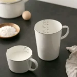 Enamel baking measuring cup with dual scale markings on a kitchen counter