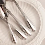 Elegant stainless steel flatware set with mirror finish arranged on a wooden table