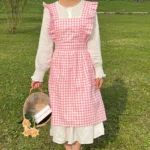 Woman wearing a cotton apron for baking with fresh plaid pattern and ruffled edges in a rustic kitchen