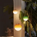 Three colorful glass pendant lamps in green, pink, and gray hanging at different heights.