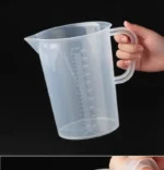 Transparent plastic lab beaker with measurement scale on kitchen counter