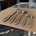 Elegant stainless steel flatware set with mirror finish arranged on a wooden table