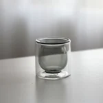 Clear double wall insulated glass mug with espresso coffee on wooden table