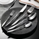 Elegant French stainless steel cutlery set with pointed tail handles on a wooden table