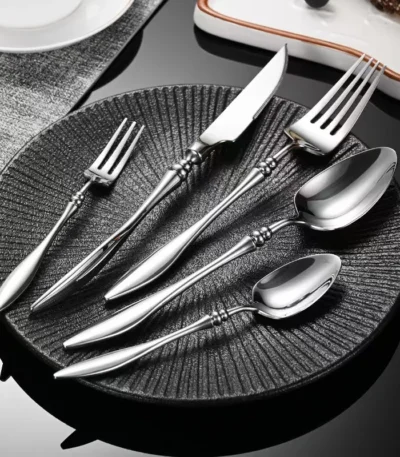 Elegant French stainless steel cutlery set with pointed tail handles on a wooden table