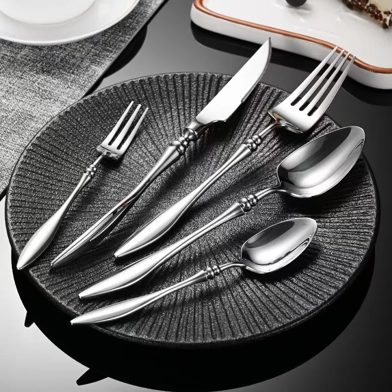Elegant French stainless steel cutlery set with pointed tail handles on a wooden table