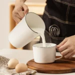 Enamel baking measuring cup with dual scale markings on a kitchen counter