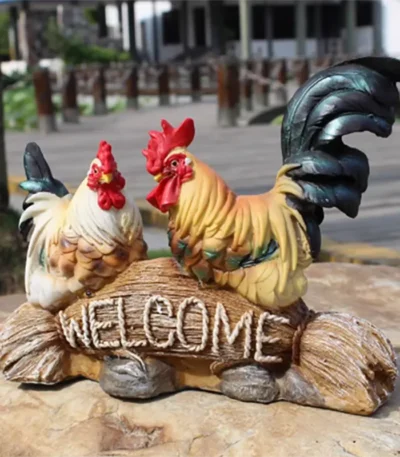 Colorful rooster garden statue standing on a wooden post in a flower garden