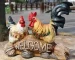 Colorful rooster garden statue standing on a wooden post in a flower garden