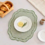 Set of four cotton linen placemats with wave edge and checkered embroidery on a wooden table