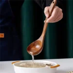 Wooden cooking utensils set with spatula, soup ladle, and rice scoop on a kitchen counter