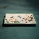Floral ceramic bottle used as lotion dispenser, on bathroom counter with mirror reflection.