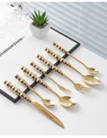 Stainless steel flatware set with ceramic pearl handles on wooden table