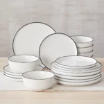 Elegant ceramic plates set with dinner plates, dessert plates, cereal bowls, and soup bowls arranged on a wooden table
