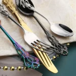 Gold flatware set with spoon, fork, and steak knife on a white tablecloth