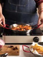 Stainless steel paella pan with double ears on a stove
