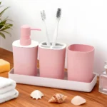 Pink ceramic soap dispenser with gold pump on a marble bathroom counter.
