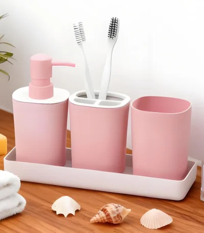 Pink ceramic soap dispenser with gold pump on a marble bathroom counter.