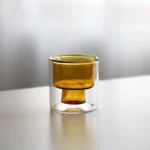 Clear double wall insulated glass mug with espresso coffee on wooden table
