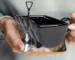 Excavator mug with spoon on a wooden table, ceramic bucket-shaped mug with a metal shovel spoon
