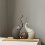 Side view of a ceramic elephant with trunk raised, against a blurred background of office decor.