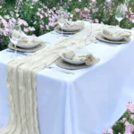 Boho cheesecloth table runner and napkins set as rustic table linens on a wooden table