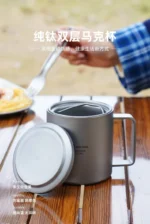 Double wall titanium mug with lid and tea strainer on a wooden table