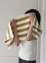 Woman relaxing on a retro striped beach towel for women by Goldoma