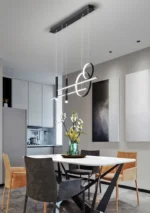 Black linear pendant light with adjustable heads over a dining table.