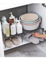 Adjustable dish drying rack with multiple tiers holding plates, bowls, and spice jars on a kitchen counter