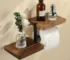 Wooden toilet paper holder mounted on a white bathroom wall with a roll of tissue hanging down.