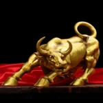 Gold copper bull statue on a polished wooden desk, side profile view.
