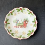 Christmas dinner plates with festive holly and berry pattern on a wooden table