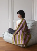 Woman relaxing on a retro striped beach towel for women by Goldoma