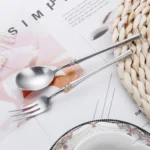 Matte gold flatware set with antique finish arranged on a wooden table