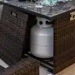 Rectangular propane fire pit table with tile top and wicker base on patio
