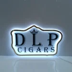 Acrylic sign with a red logo, glowing in a dimly lit office with a laptop in background.
