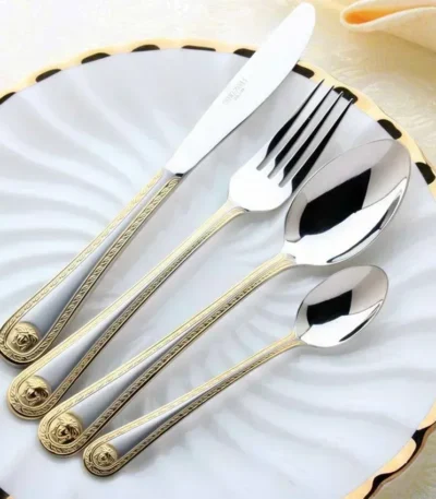 Gold plated flatware set with vintage Western engraving on a dark wooden table